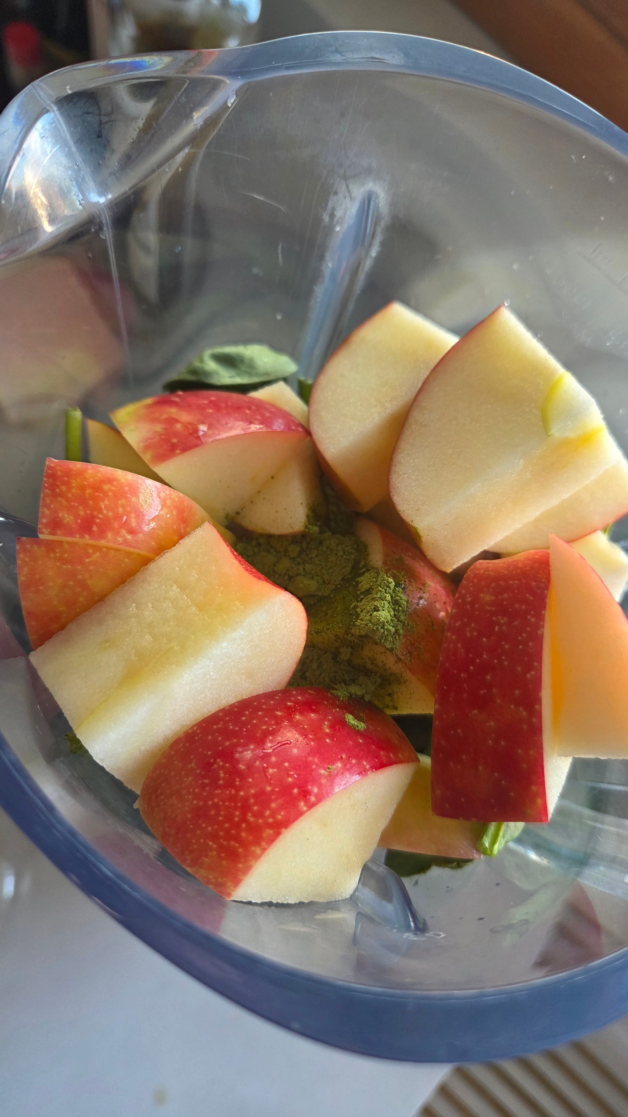 Apple slices and matcha powder loaded into the blender ready to blend