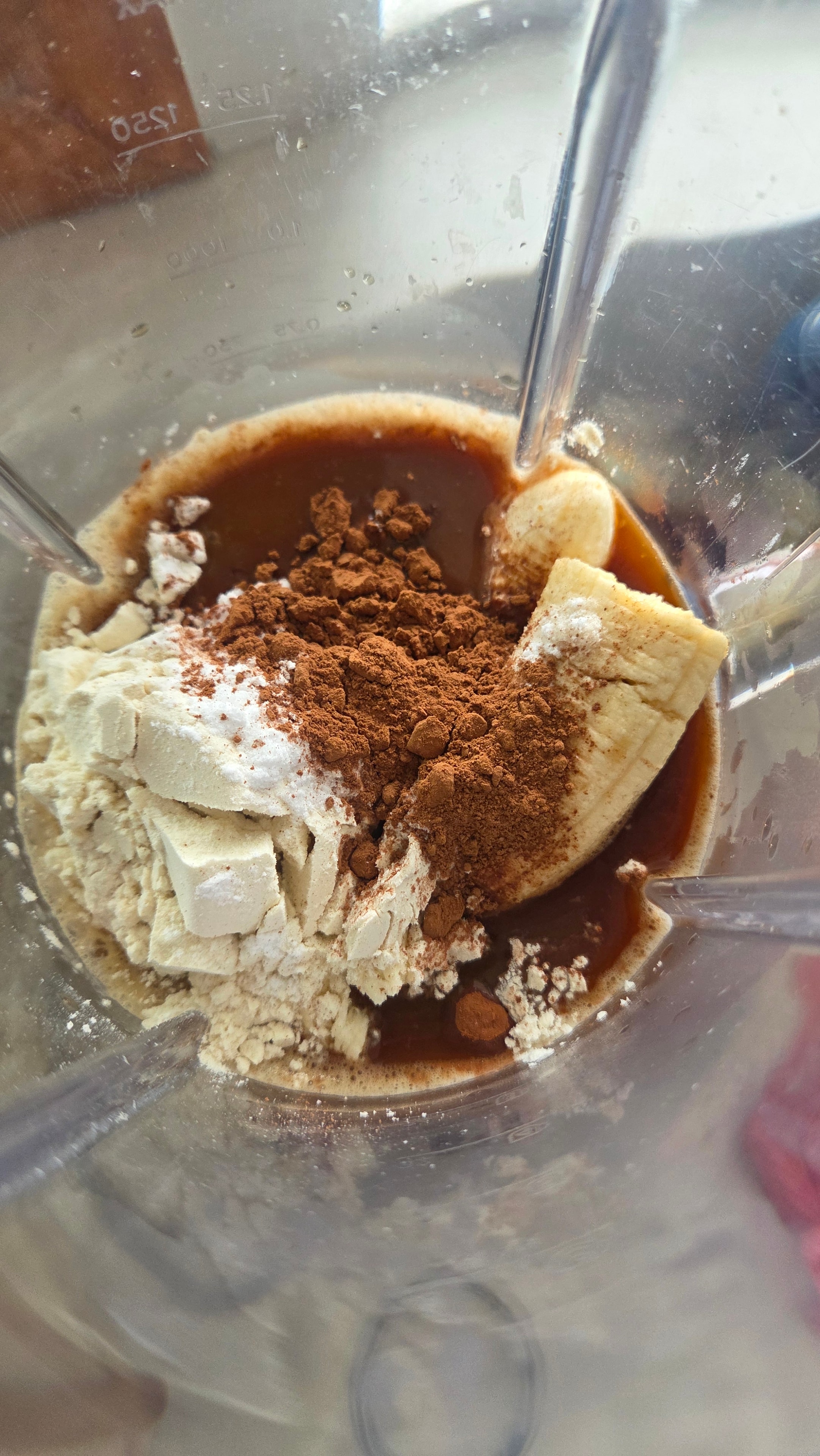 Banana, cocoa powder, whey protein, and coffee loaded into the blender