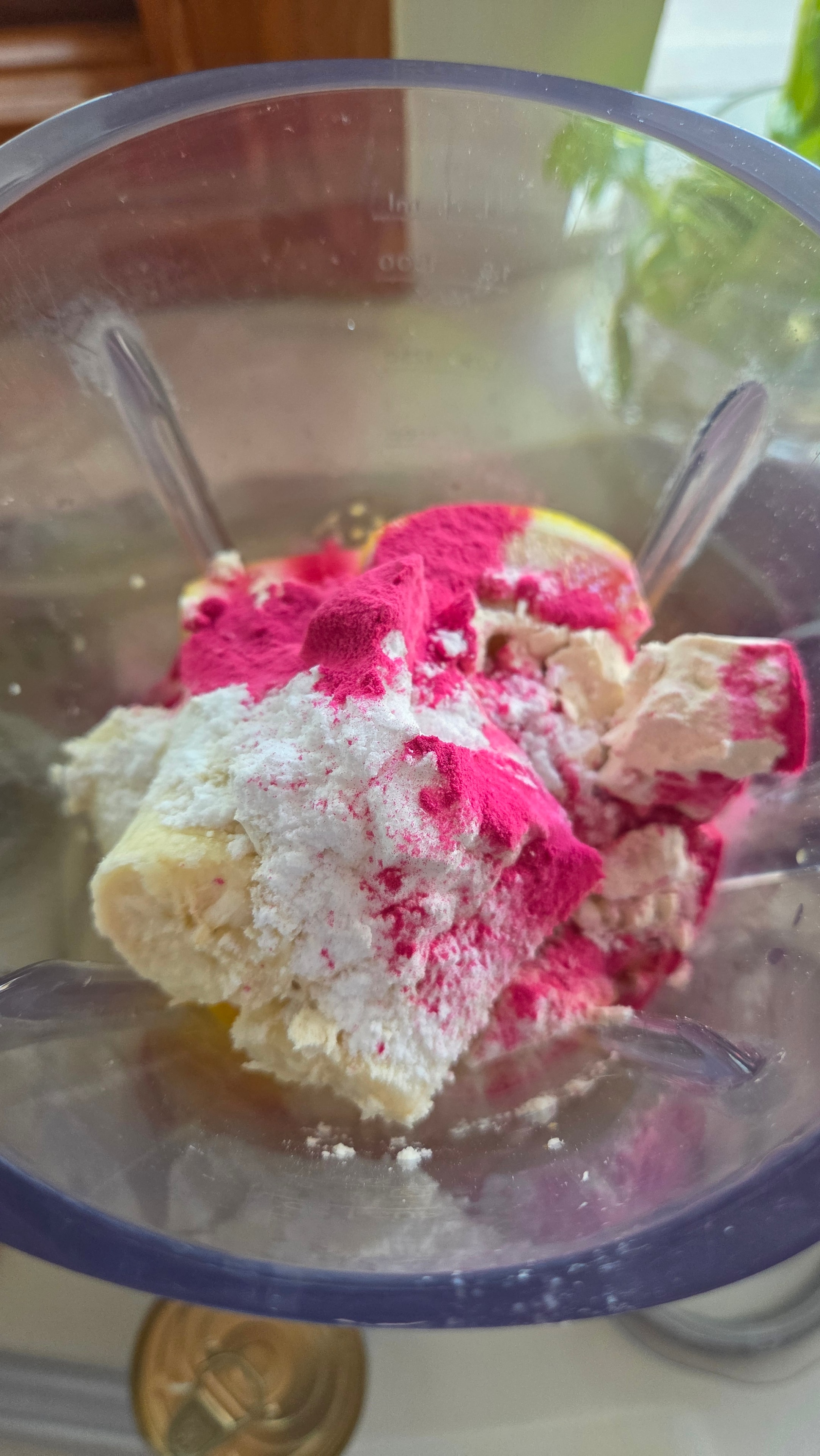 Blender with pink pitaya powder and banana ready to blend