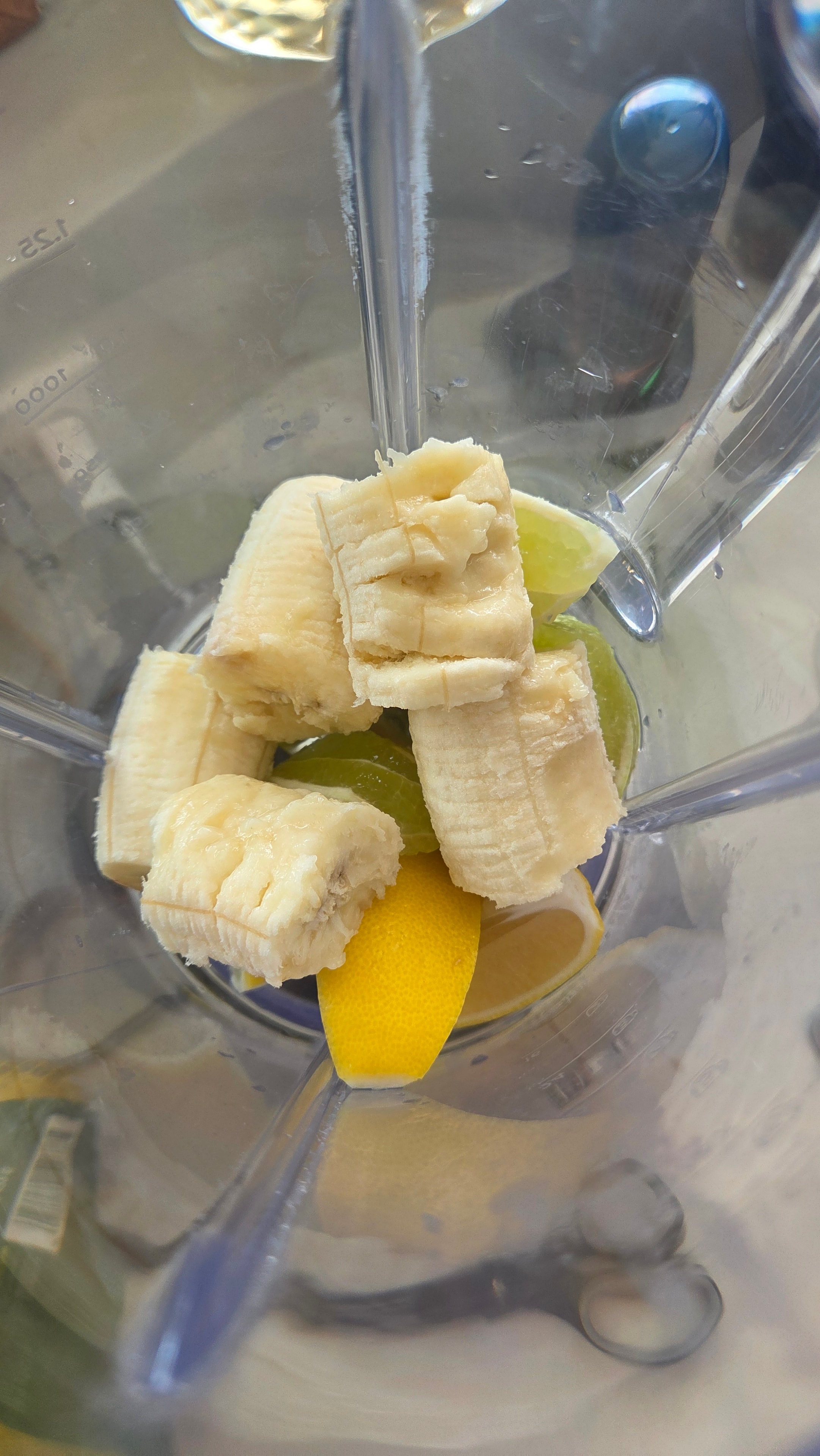 Banana, lemon, and lime in the blender with orange juice and ice — the first blend
