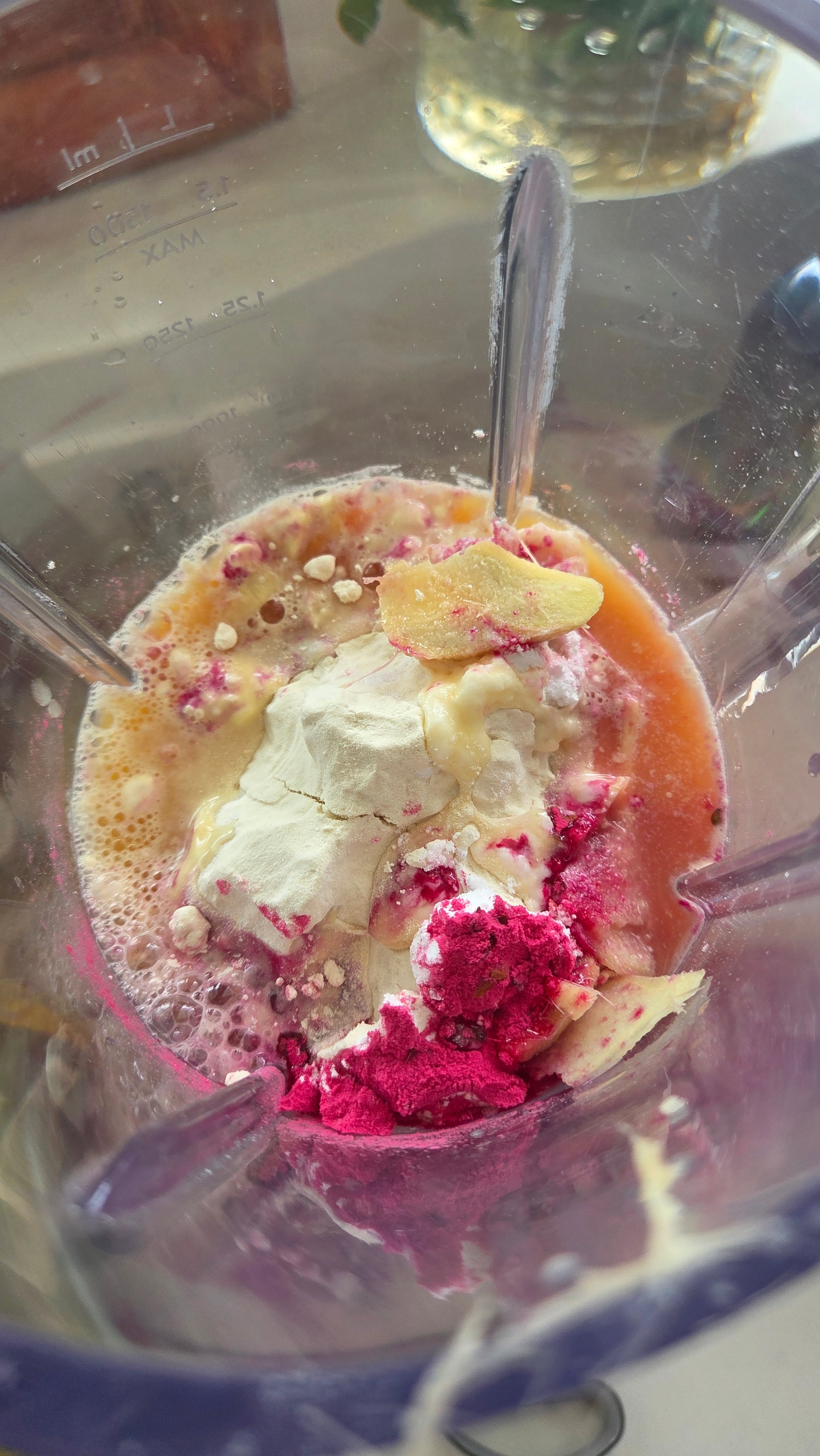 The blender running on smoothie setting — pink pitaya smoothie mid-blend